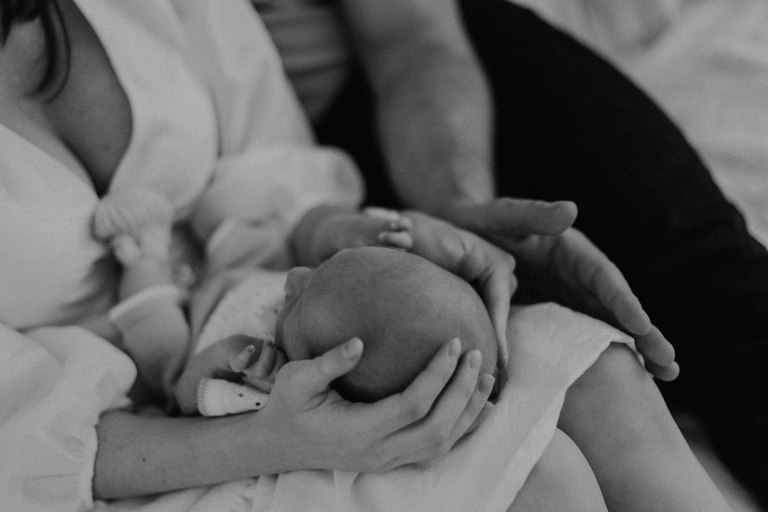 Baby in den Armen seiner Eltern in Schwarzweiß